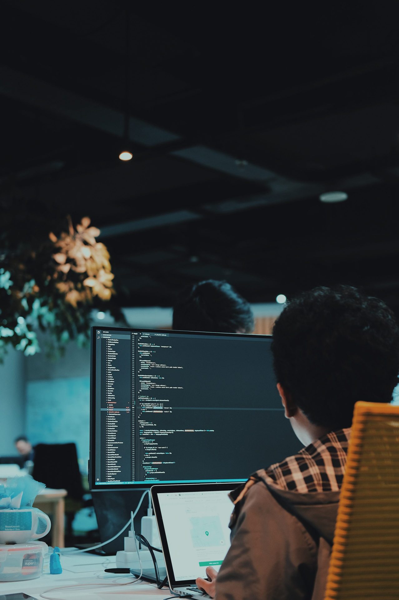 Man behind computer screen showing data and code in a dark office environment